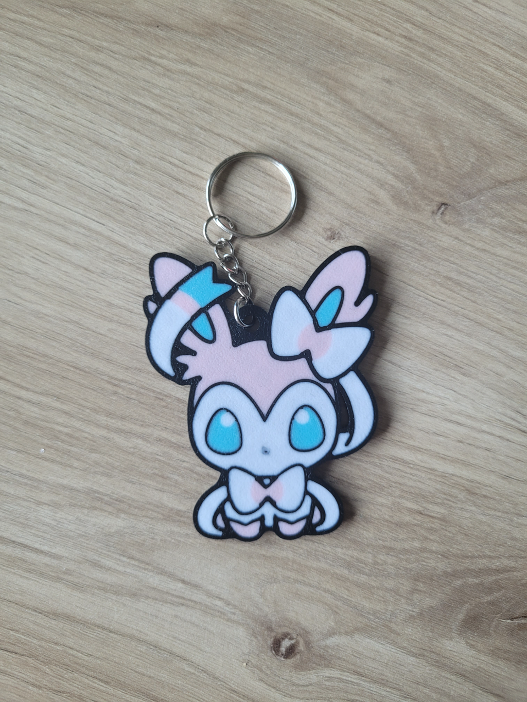 Keychain with a cartoon character on a wooden surface Sylveon