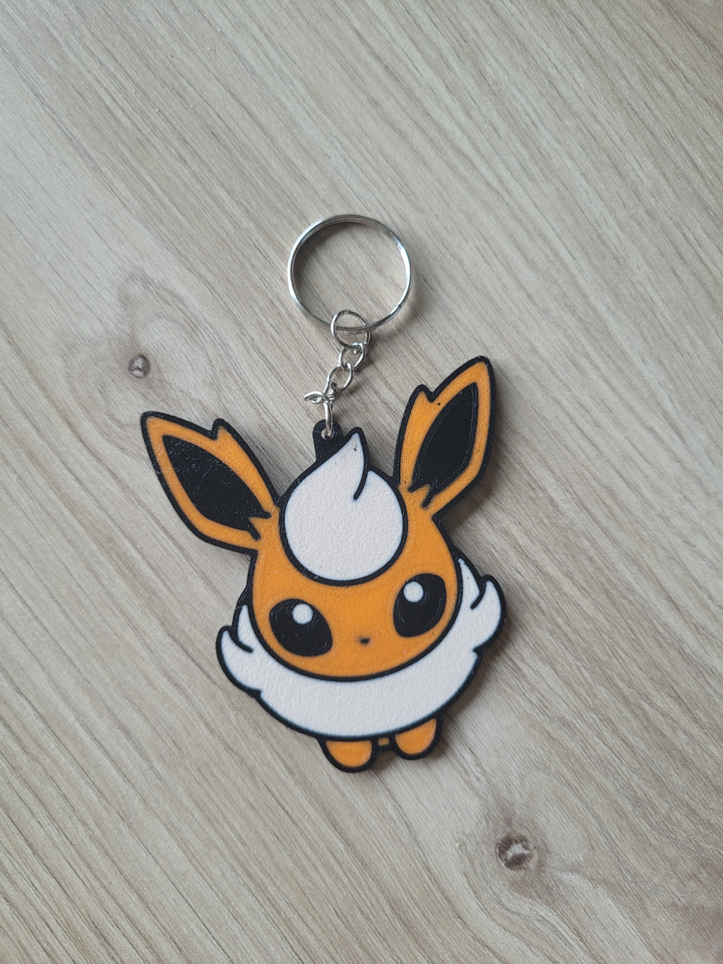 Keychain with a cartoon character on a wooden surface Flareon